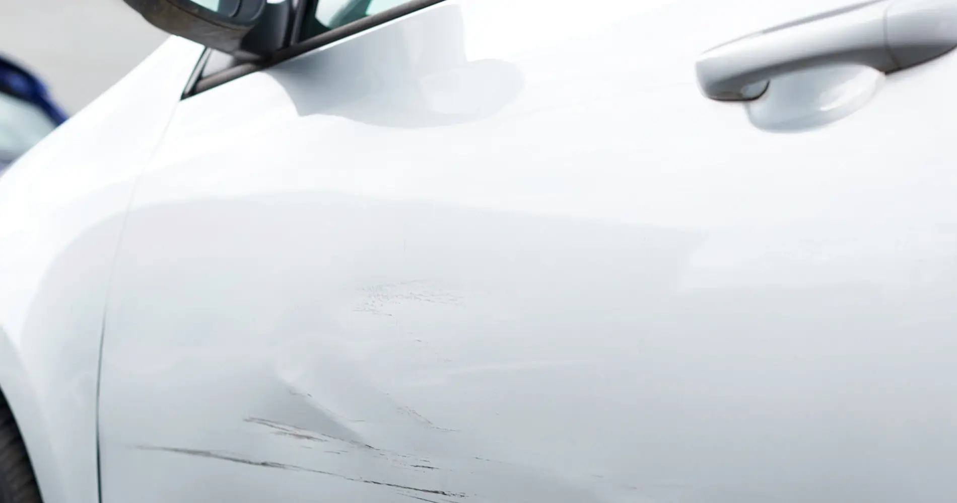 Weiße Motorhaube mit leichten Lackschäden und Kratzern