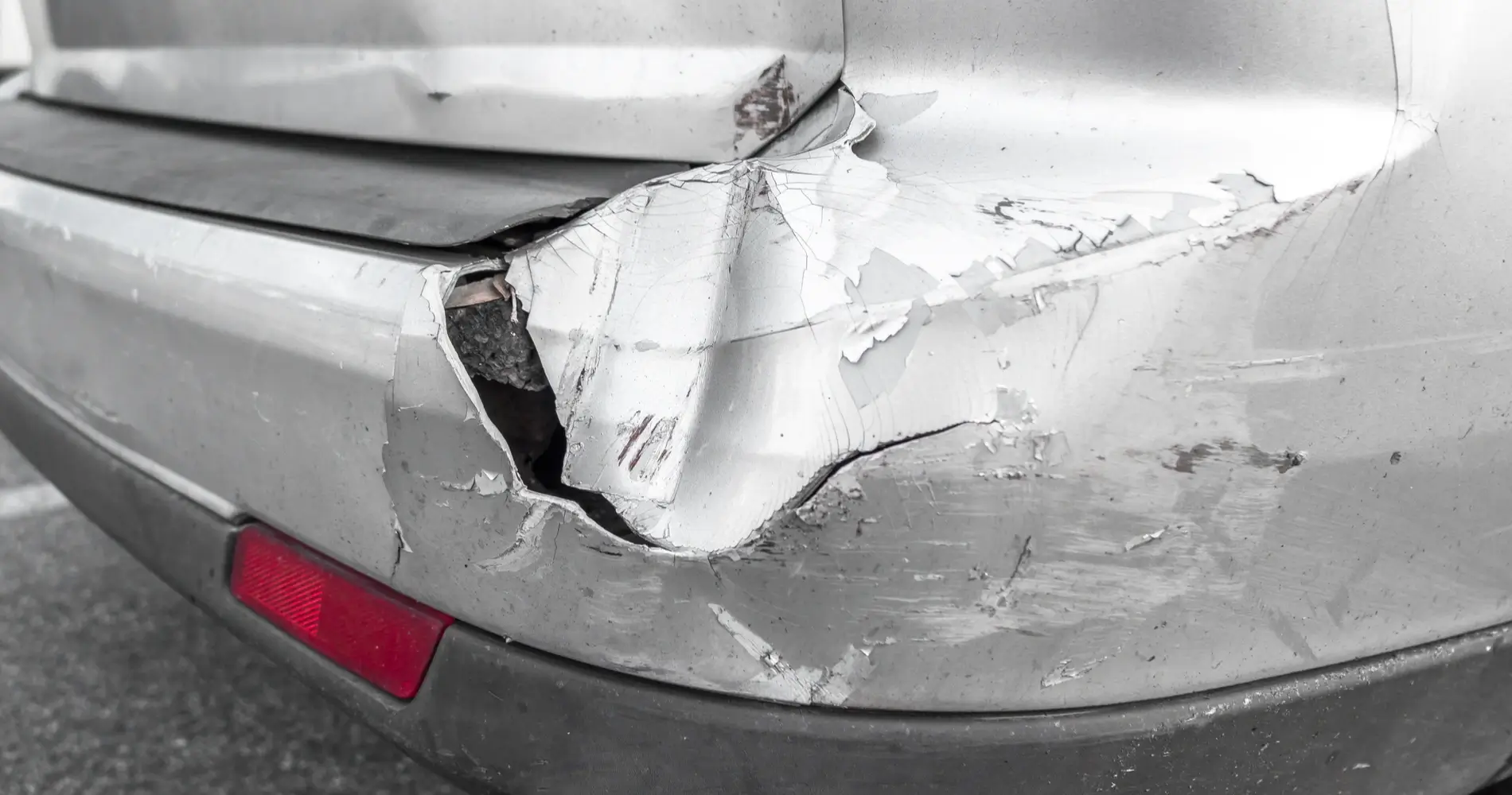 Detailaufnahme silbernes Auto mit Blechschaden an der rechten Fahrzeugseite
